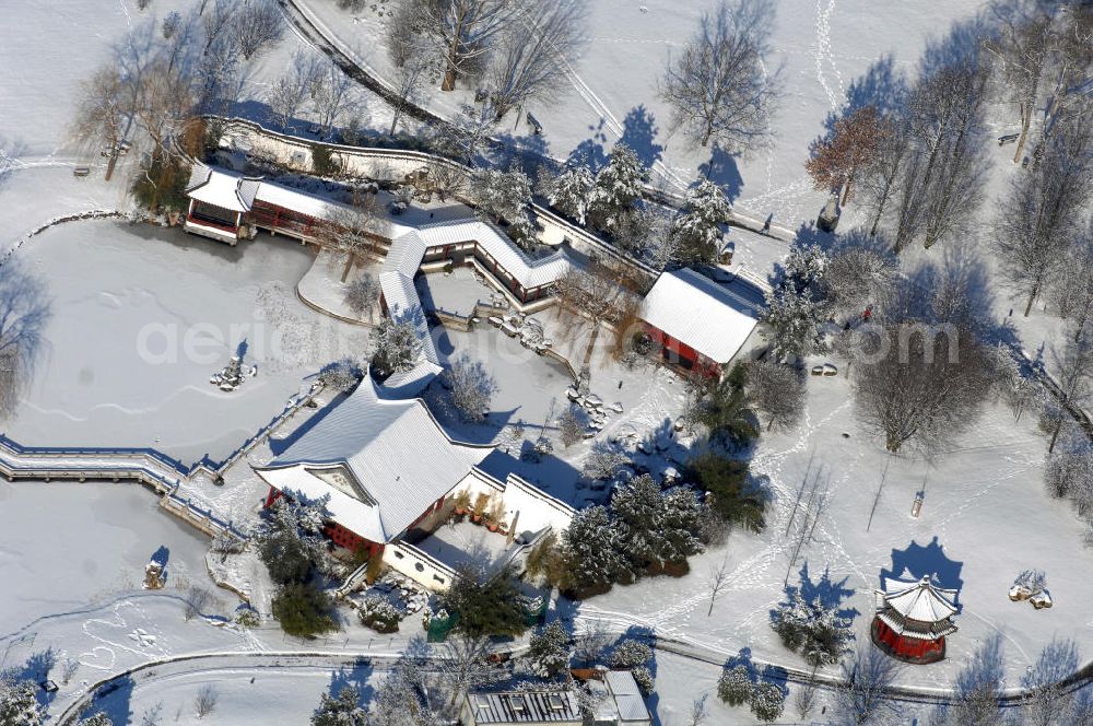 Aerial photograph Berlin - Blick auf den winterlich verschneiten Chinesischen Garten im Erholungspark Marzahn. Der Erholungspark Marzahn liegt im Berliner Bezirk Marzahn-Hellersdorf am nördlichen Fuß des Kienbergs und wurde am 9. Mai 1987 anlässlich der 750-Jahr-Feier von Berlin als Berliner Gartenschau und Geschenk der Gärtner an die Hauptstadt der DDR (Ost-Berlin) eröffnet und sollte somit ein Gegenstück zum Britzer Garten im damaligen West-Berlin darstellen. 1991 wurde die Berliner Gartenschau nicht nur in Erholungspark Marzahn umbenannt, sondern auch umgebaut: Große Spiel- und Liegewiesen sowie neue Spielplätze entstanden, Bäume wurden gepflanzt und Sondergärten überarbeitet und erweitert. Der neu gestaltete Park sollte den 300.000 Bewohnern der umliegenden Großsiedlungen als vielfältig nutzbare Erholungslandschaft dienen. Seit Oktober 2000 ist diese durch ihre Gärten der Welt auch weit über die Stadtgrenzen hinaus bekannt. 2005 wurde der Chinesische Garten im Erholungspark Marzahn als drittschönste Parkanlage Deutschlands ausgezeichnet. Außerdem gehört der Erholungspark zu den 365 Orten im Land der Ideen.