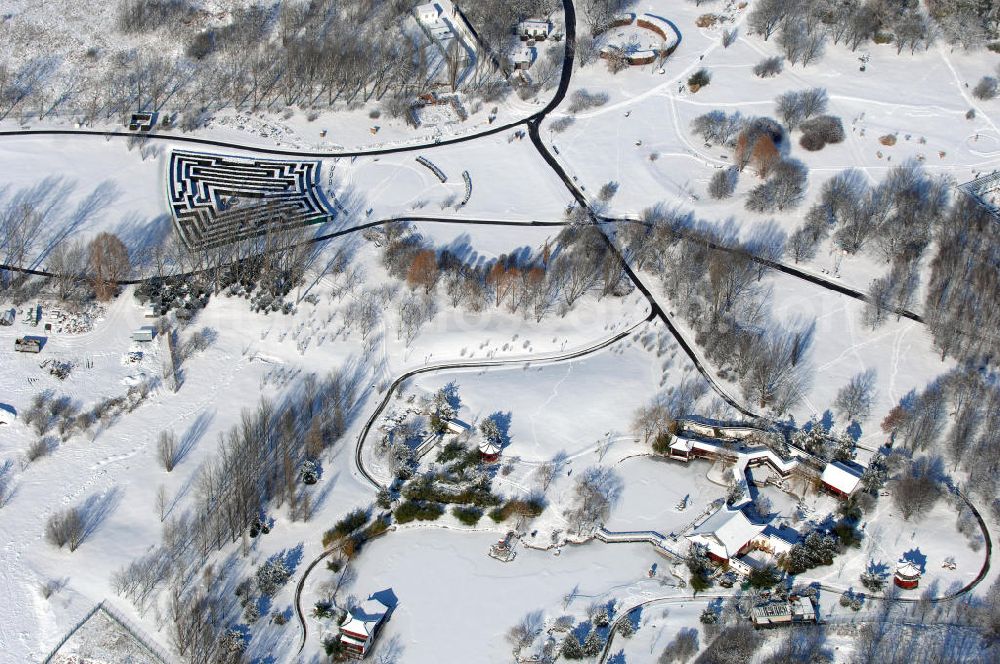 Berlin from above - Blick auf den winterlich verschneiten Chinesischen Garten im Erholungspark Marzahn. Der Erholungspark Marzahn liegt im Berliner Bezirk Marzahn-Hellersdorf am nördlichen Fuß des Kienbergs und wurde am 9. Mai 1987 anlässlich der 750-Jahr-Feier von Berlin als Berliner Gartenschau und Geschenk der Gärtner an die Hauptstadt der DDR (Ost-Berlin) eröffnet und sollte somit ein Gegenstück zum Britzer Garten im damaligen West-Berlin darstellen. 1991 wurde die Berliner Gartenschau nicht nur in Erholungspark Marzahn umbenannt, sondern auch umgebaut: Große Spiel- und Liegewiesen sowie neue Spielplätze entstanden, Bäume wurden gepflanzt und Sondergärten überarbeitet und erweitert. Der neu gestaltete Park sollte den 300.000 Bewohnern der umliegenden Großsiedlungen als vielfältig nutzbare Erholungslandschaft dienen. Seit Oktober 2000 ist diese durch ihre Gärten der Welt auch weit über die Stadtgrenzen hinaus bekannt. 2005 wurde der Chinesische Garten im Erholungspark Marzahn als drittschönste Parkanlage Deutschlands ausgezeichnet. Außerdem gehört der Erholungspark zu den 365 Orten im Land der Ideen.