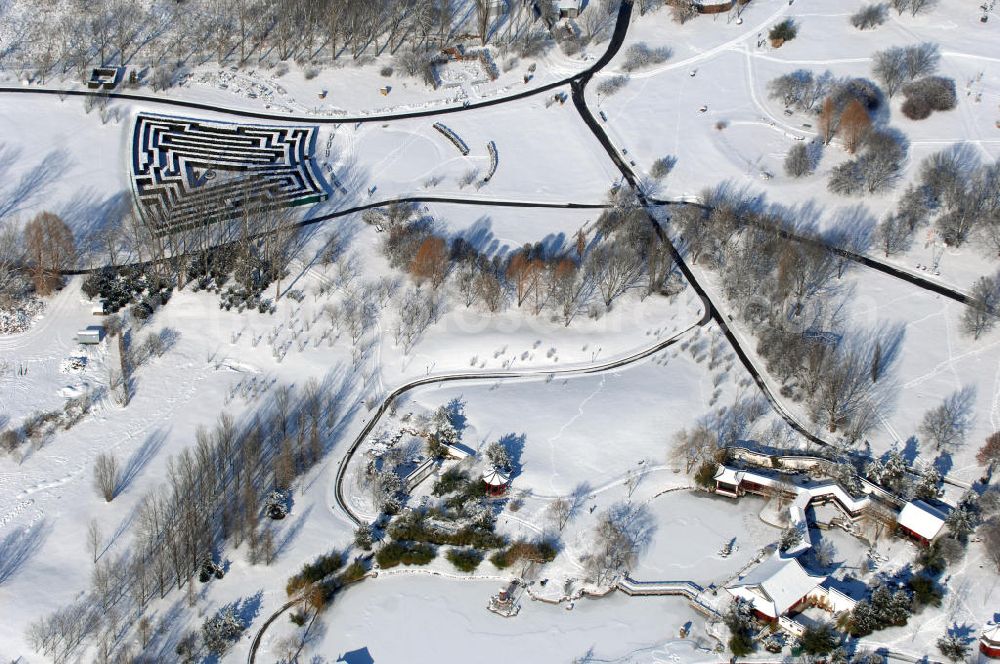 Berlin from the bird's eye view: Blick auf den winterlich verschneiten Chinesischen Garten im Erholungspark Marzahn. Der Erholungspark Marzahn liegt im Berliner Bezirk Marzahn-Hellersdorf am nördlichen Fuß des Kienbergs und wurde am 9. Mai 1987 anlässlich der 750-Jahr-Feier von Berlin als Berliner Gartenschau und Geschenk der Gärtner an die Hauptstadt der DDR (Ost-Berlin) eröffnet und sollte somit ein Gegenstück zum Britzer Garten im damaligen West-Berlin darstellen. 1991 wurde die Berliner Gartenschau nicht nur in Erholungspark Marzahn umbenannt, sondern auch umgebaut: Große Spiel- und Liegewiesen sowie neue Spielplätze entstanden, Bäume wurden gepflanzt und Sondergärten überarbeitet und erweitert. Der neu gestaltete Park sollte den 300.000 Bewohnern der umliegenden Großsiedlungen als vielfältig nutzbare Erholungslandschaft dienen. Seit Oktober 2000 ist diese durch ihre Gärten der Welt auch weit über die Stadtgrenzen hinaus bekannt. 2005 wurde der Chinesische Garten im Erholungspark Marzahn als drittschönste Parkanlage Deutschlands ausgezeichnet. Außerdem gehört der Erholungspark zu den 365 Orten im Land der Ideen.