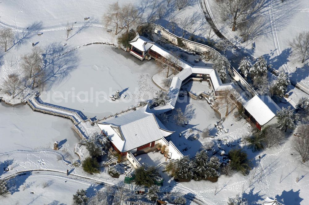 Aerial photograph Berlin - Blick auf den winterlich verschneiten Chinesischen Garten im Erholungspark Marzahn. Der Erholungspark Marzahn liegt im Berliner Bezirk Marzahn-Hellersdorf am nördlichen Fuß des Kienbergs und wurde am 9. Mai 1987 anlässlich der 750-Jahr-Feier von Berlin als Berliner Gartenschau und Geschenk der Gärtner an die Hauptstadt der DDR (Ost-Berlin) eröffnet und sollte somit ein Gegenstück zum Britzer Garten im damaligen West-Berlin darstellen. 1991 wurde die Berliner Gartenschau nicht nur in Erholungspark Marzahn umbenannt, sondern auch umgebaut: Große Spiel- und Liegewiesen sowie neue Spielplätze entstanden, Bäume wurden gepflanzt und Sondergärten überarbeitet und erweitert. Der neu gestaltete Park sollte den 300.000 Bewohnern der umliegenden Großsiedlungen als vielfältig nutzbare Erholungslandschaft dienen. Seit Oktober 2000 ist diese durch ihre Gärten der Welt auch weit über die Stadtgrenzen hinaus bekannt. 2005 wurde der Chinesische Garten im Erholungspark Marzahn als drittschönste Parkanlage Deutschlands ausgezeichnet. Außerdem gehört der Erholungspark zu den 365 Orten im Land der Ideen.