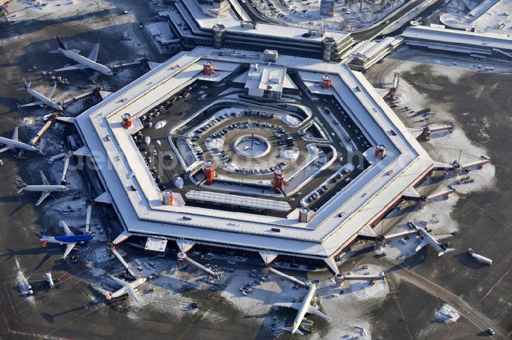 Berlin from the bird's eye view: Winterlich verschneiter Blick auf Areal des Flughafen Berlin- Tegel. Am Abfertigungsterminal stehen Flugzeuge der DELTA , AIR Berlin und BRITISH AIRWAYS. View of the area of the airport Berlin-Tegel with the two runways. On the Terminal stand aircraft - operated by DELTA, AIR BERLIN and BRITISH AIRWAYS.