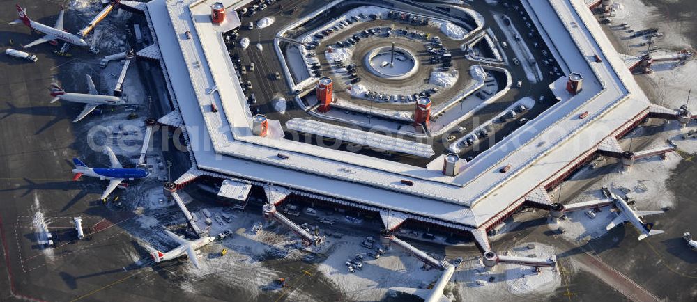 Aerial image Berlin - Winterlich verschneiter Blick auf Areal des Flughafen Berlin- Tegel. Am Abfertigungsterminal stehen Flugzeuge der DELTA , AIR Berlin und BRITISH AIRWAYS. View of the area of the airport Berlin-Tegel with the two runways. On the Terminal stand aircraft - operated by DELTA, AIR BERLIN and BRITISH AIRWAYS.