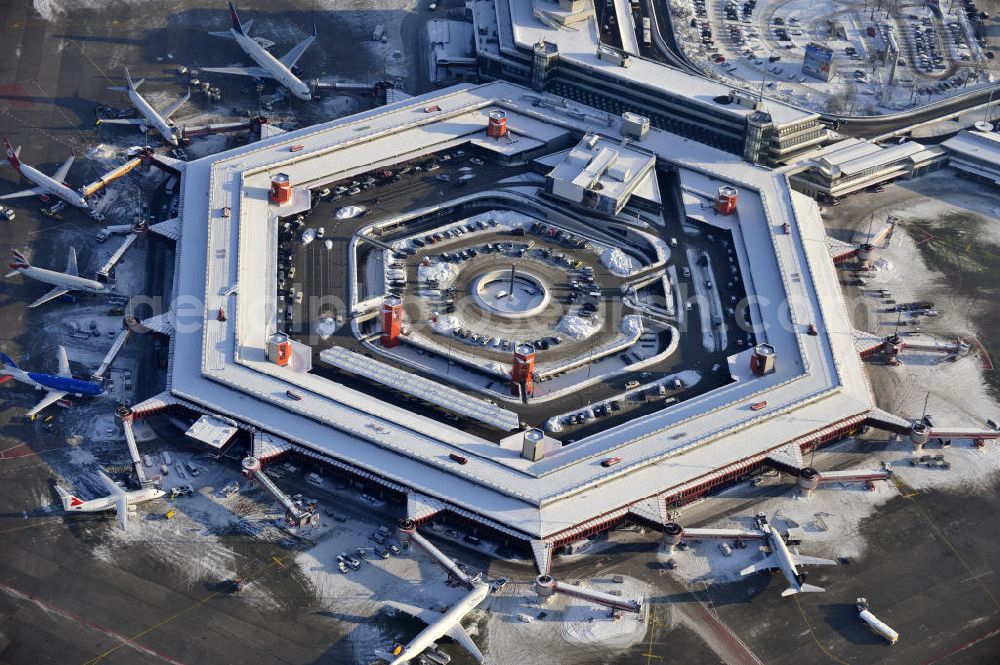 Berlin from the bird's eye view: Winterlich verschneiter Blick auf Areal des Flughafen Berlin- Tegel. Am Abfertigungsterminal stehen Flugzeuge der DELTA , AIR Berlin und BRITISH AIRWAYS. View of the area of the airport Berlin-Tegel with the two runways. On the Terminal stand aircraft - operated by DELTA, AIR BERLIN and BRITISH AIRWAYS.