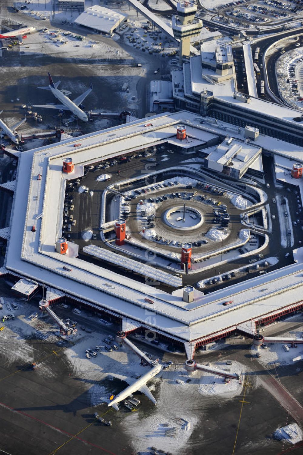 Aerial image Berlin - Winterlich verschneiter Blick auf Areal des Flughafen Berlin- Tegel. Am Abfertigungsterminal stehen Flugzeuge der DELTA , AIR Berlin und BRITISH AIRWAYS. View of the area of the airport Berlin-Tegel with the two runways. On the Terminal stand aircraft - operated by DELTA, AIR BERLIN and BRITISH AIRWAYS.