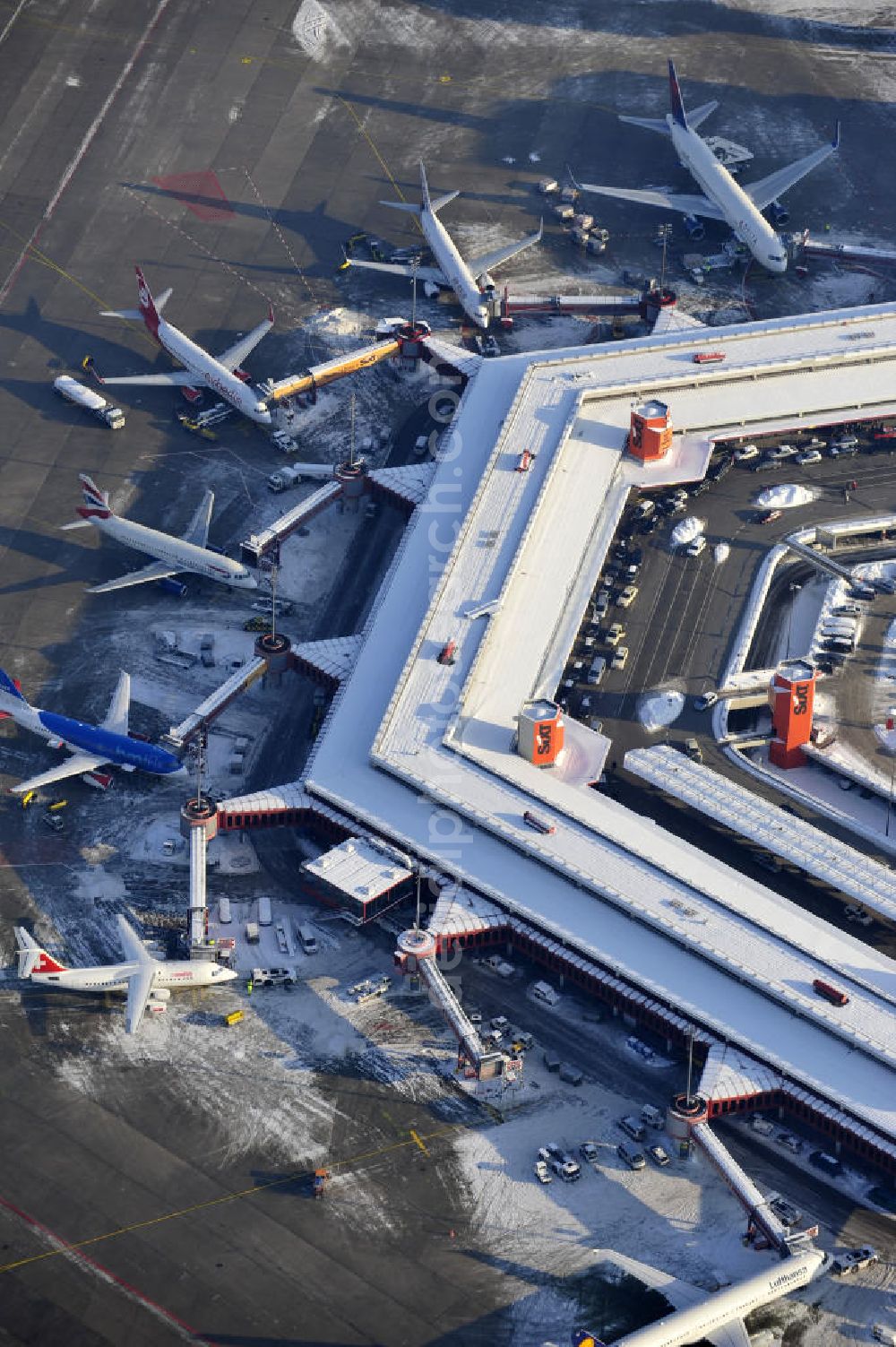 Berlin from the bird's eye view: Winterlich verschneiter Blick auf Areal des Flughafen Berlin- Tegel. Am Abfertigungsterminal stehen Flugzeuge der DELTA , AIR Berlin und BRITISH AIRWAYS. View of the area of the airport Berlin-Tegel with the two runways. On the Terminal stand aircraft - operated by DELTA, AIR BERLIN and BRITISH AIRWAYS.