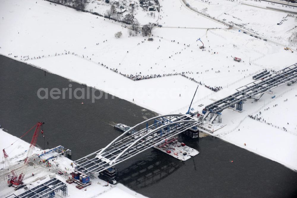 Dresden from the bird's eye view: Winterlich verschneites Einschwimmen der Waldschlösschenbrücke in Dresden über die Elbe mit den Stahlträgern der belgischen Firma Victor Buyck Steel Constructions nach Vorgaben des Büros AWB Architekten Architekturbüro Bauer BDA und Bauleistungen der EUROVIA Beton GmbH. View the construction site of Waldschlösschen bridge over the Elbe in Dresden / Saxony.