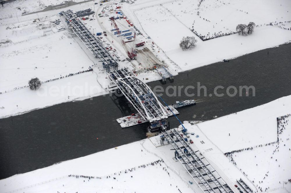 Aerial photograph Dresden - Winterlich verschneites Einschwimmen der Waldschlösschenbrücke in Dresden über die Elbe mit den Stahlträgern der belgischen Firma Victor Buyck Steel Constructions nach Vorgaben des Büros AWB Architekten Architekturbüro Bauer BDA und Bauleistungen der EUROVIA Beton GmbH. View the construction site of Waldschlösschen bridge over the Elbe in Dresden / Saxony.