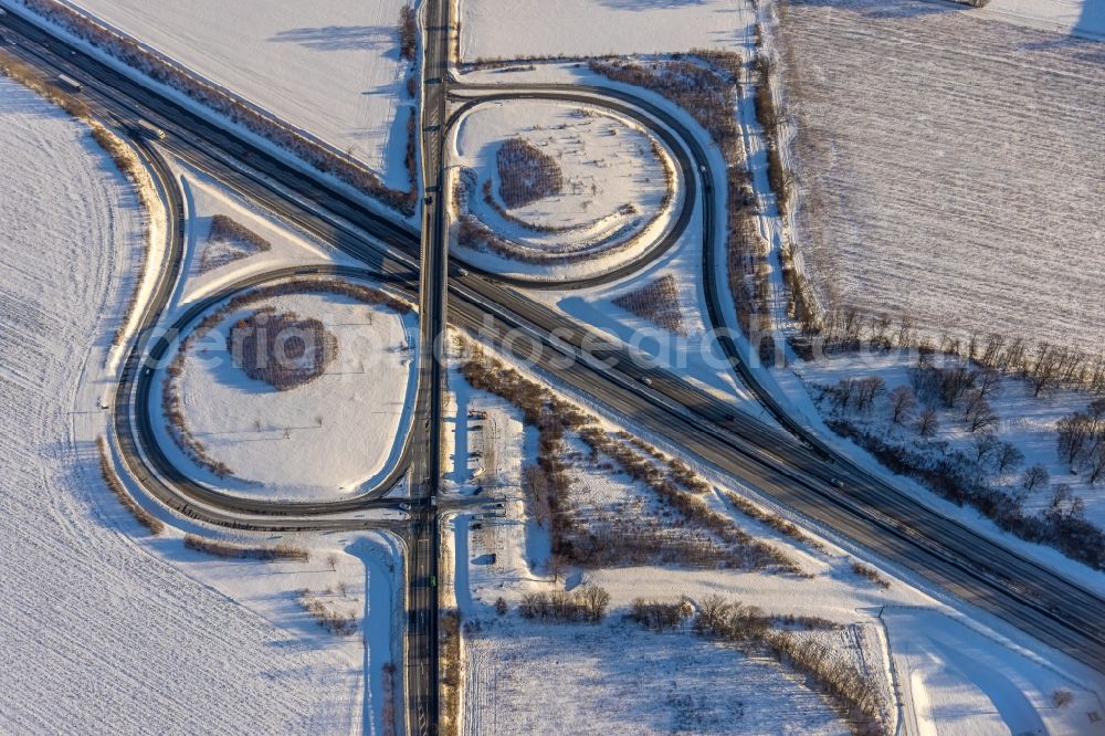 Werl from the bird's eye view: Wintry snowy routing and traffic lanes during the highway exit and access the motorway A 44 Werl-Sued in the district Westoennen in Werl at Ruhrgebiet in the state North Rhine-Westphalia, Germany