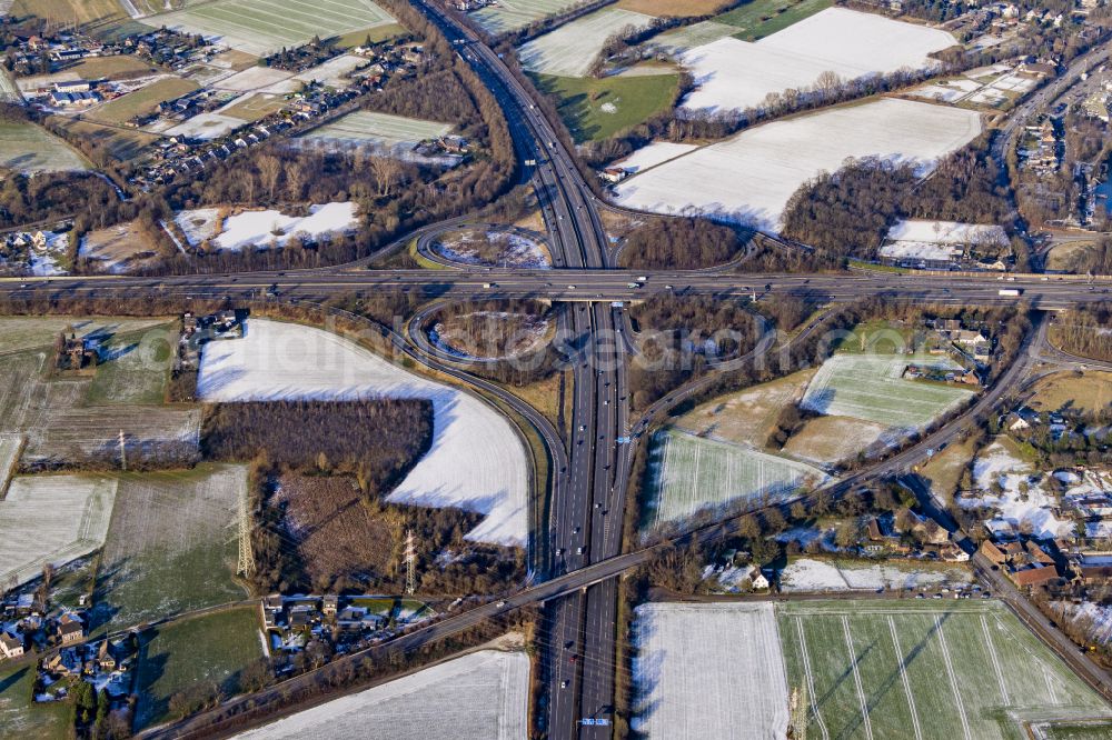 Bettenkamp from the bird's eye view: Wintry snowy autumnal discolored view of vegetation Traffic routing and lanes in the road layout of the Autobahn junction of the BAB A40 and BAB A57 at Kreuz Moers - laid out in the shape of a cloverleaf in Bettenkamp in the state of North Rhine-Westphalia, Germany