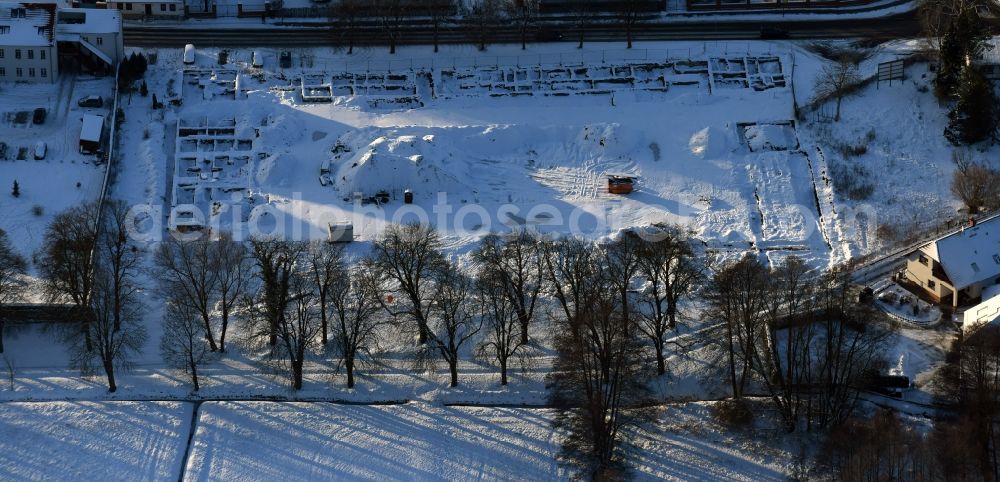 Altlandsberg from above - Wintry snowy Construction site with development works and embankments works and archaeological digging work in Altlandsberg in the state Brandenburg