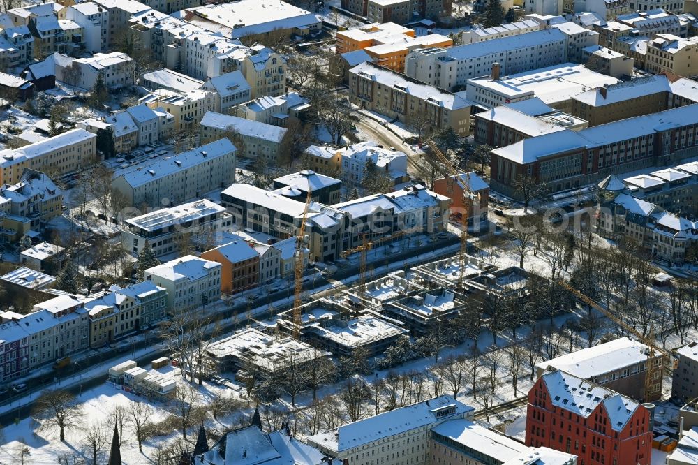 Rostock from the bird's eye view: Wintry snowy construction site to build a new multi-family residential complex Am Rosengarten on August-Bebel-Strasse - Wallstrasse in the district Stadtmitte in Rostock in the state Mecklenburg - Western Pomerania, Germany