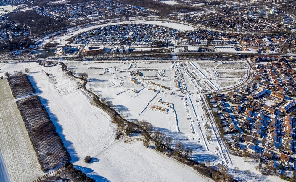 Duisburg from the bird's eye view: Wintry snowy residential area construction site of a mixed development with multi-family houses and single-family houses- New building at the Am Alten Angerbach in the district Huckingen in Duisburg in the state North Rhine-Westphalia, Germany