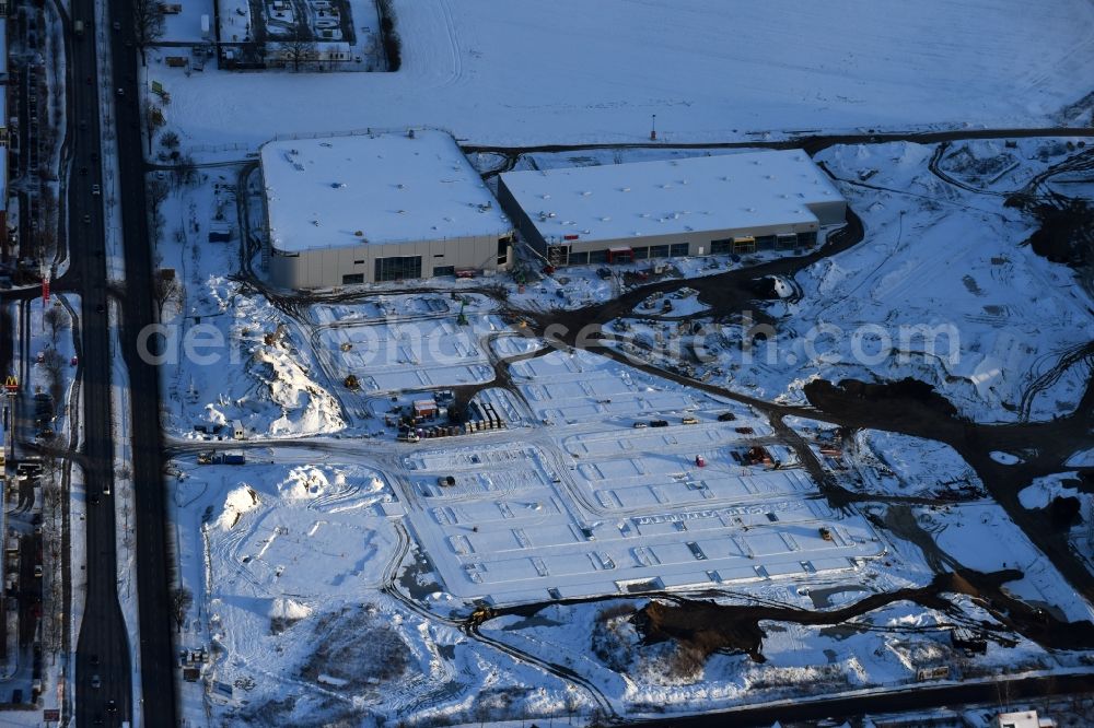 Berlin from the bird's eye view: Wintry snowy construction site for the new building home-center of the Porta-Group at Pilgramer street in the district Mahlsdorf in Berlin