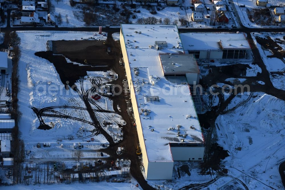 Berlin from the bird's eye view: Wintry snowy construction site for the new building home-center of the Porta-Group at Pilgramer street in the district Mahlsdorf in Berlin