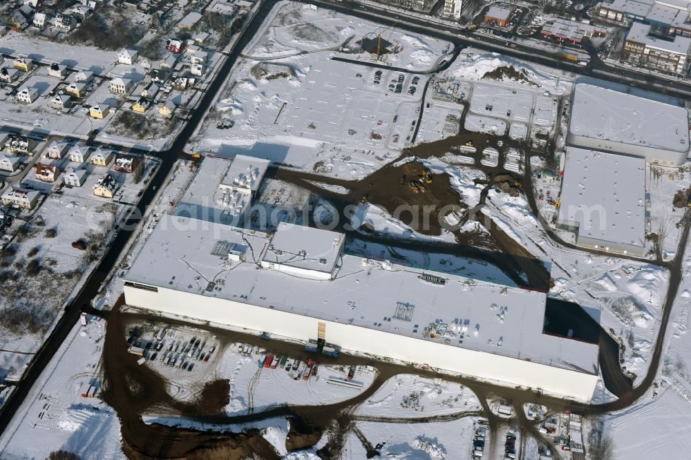 Berlin from the bird's eye view: Wintry snowy construction site for the new building home-center of the Porta-Group at Pilgramer street in the district Mahlsdorf in Berlin