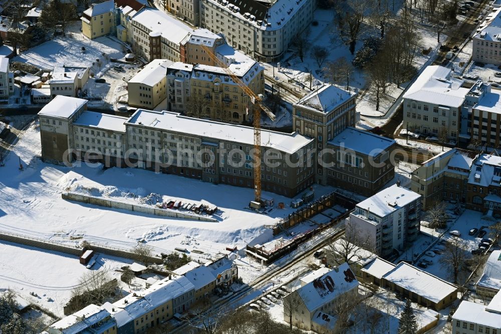 Rostock from the bird's eye view: Wintry snowy construction site for the multi-family residential building Am Gueterbahnhof in Rostock in the state Mecklenburg - Western Pomerania, Germany