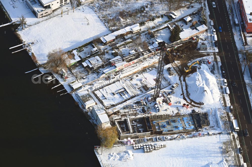 Aerial image Berlin - Wintry snowy construction site for the multi-family residential building on the banks of the Spree river on street Schnellerstrasse in the district Schoeneweide in Berlin, Germany