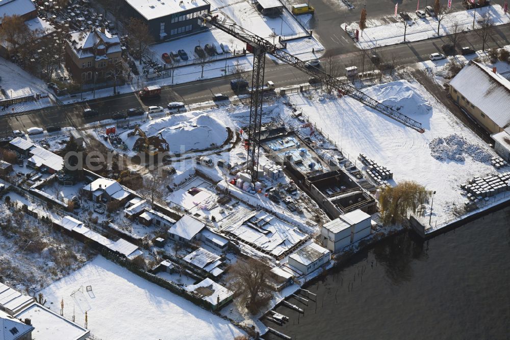Berlin from above - Wintry snowy construction site for the multi-family residential building on the banks of the Spree river on street Schnellerstrasse in the district Schoeneweide in Berlin, Germany