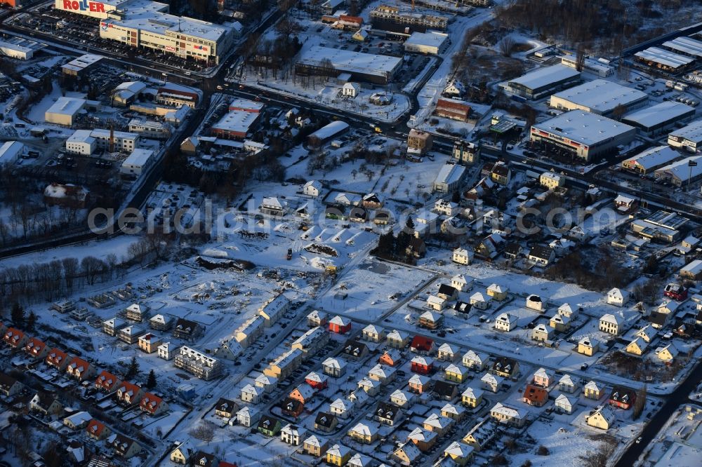 Berlin from above - Wintry snowy construction sites for new construction residential area of detached housing estate at Theodorstreet at Theordorpark in the district Mahlsdorf in Berlin. Building-ower is the company Bonava