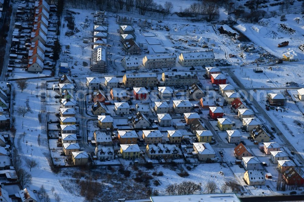 Berlin from the bird's eye view: Wintry snowy construction sites for new construction residential area of detached housing estate at Theodorstreet at Theordorpark in the district Mahlsdorf in Berlin. Building-ower is the company Bonava