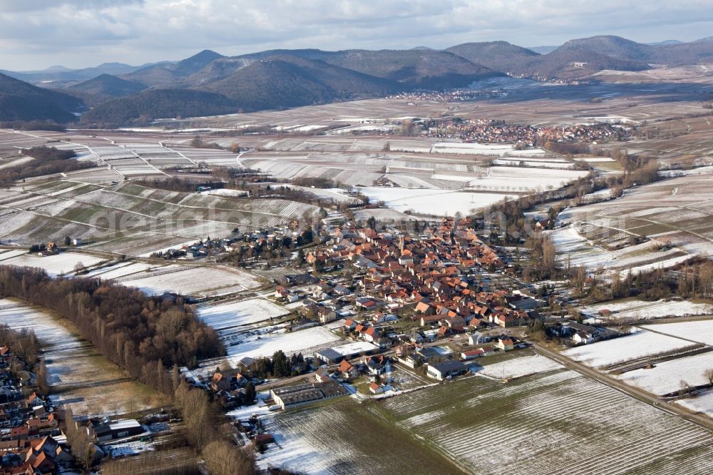 Heuchelheim-Klingen from the bird's eye view: Wintry snowy Village - view on the edge of agricultural fields and farmland in the district Heuchelheim in Heuchelheim-Klingen in the state Rhineland-Palatinate, Germany