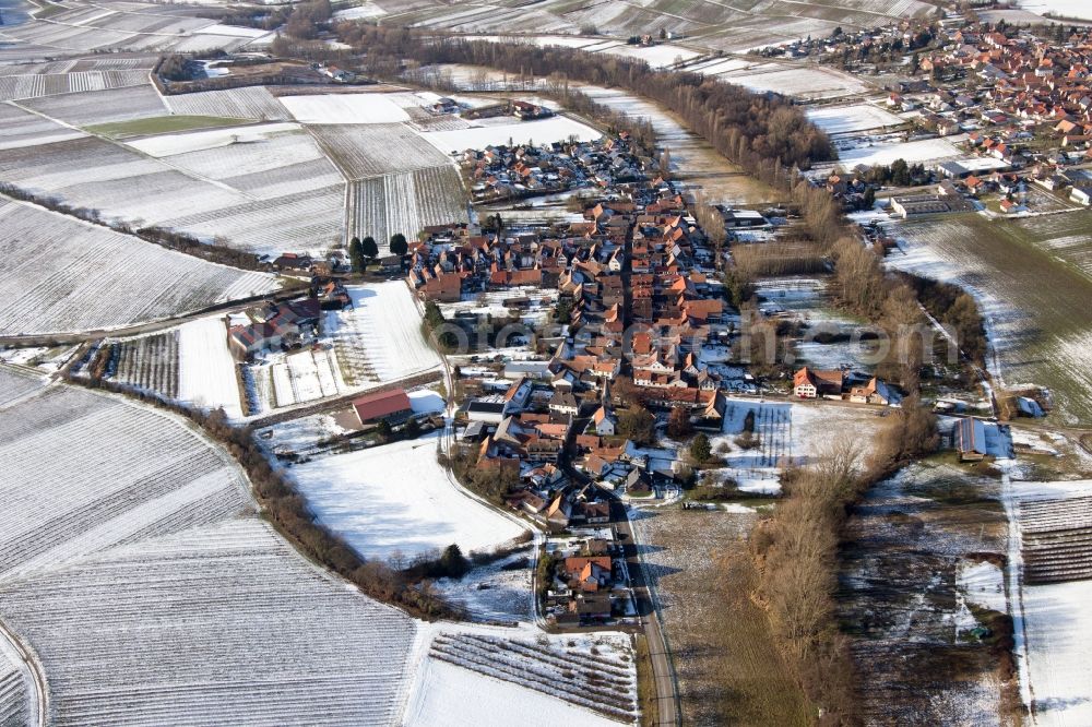 Heuchelheim-Klingen from the bird's eye view: Wintry snowy Village - view on the edge of agricultural fields and farmland in the district Klingen in Heuchelheim-Klingen in the state Rhineland-Palatinate, Germany