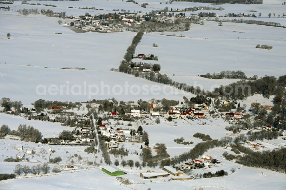 Krumbeck from above - Wintry snowy agricultural land and field boundaries surround the settlement area of the village in Krumbeck in the state Mecklenburg - Western Pomerania, Germany