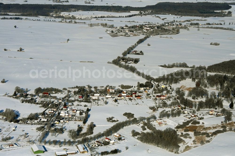 Krumbeck from the bird's eye view: Wintry snowy agricultural land and field boundaries surround the settlement area of the village in Krumbeck in the state Mecklenburg - Western Pomerania, Germany