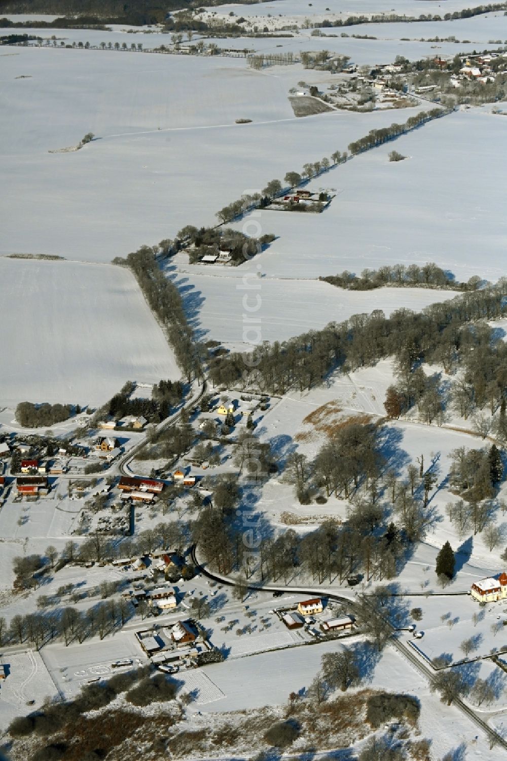 Krumbeck from the bird's eye view: Wintry snowy agricultural land and field boundaries surround the settlement area of the village in Krumbeck in the state Mecklenburg - Western Pomerania, Germany