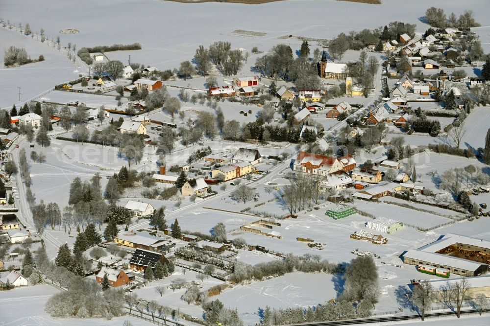 Rehberg from the bird's eye view: Wintry snowy agricultural land and field boundaries surround the settlement area of the village in Rehberg in the state Mecklenburg - Western Pomerania, Germany