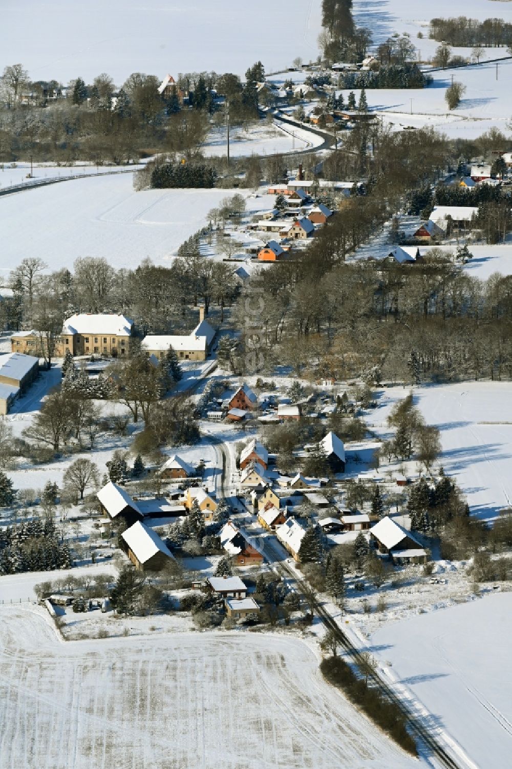 Aerial photograph Tentzerow - Wintry snowy agricultural land and field boundaries surround the settlement area of the village in Tentzerow in the state Mecklenburg - Western Pomerania, Germany