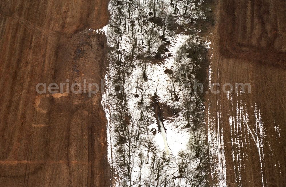 Aerial image Neulewin - Wintry snowy Agricultural fields embossed of soil erosion and ice and snow and water structures in Neulewin in the state Brandenburg, Germany