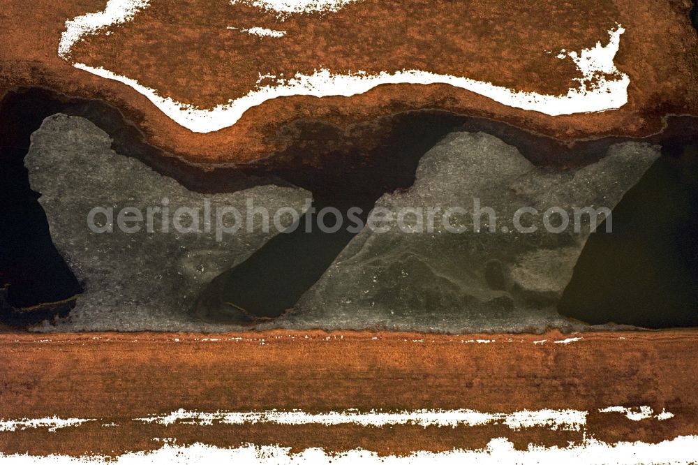 Neulewin from the bird's eye view: Wintry snowy Agricultural fields embossed of soil erosion and ice and snow and water structures in Neulewin in the state Brandenburg, Germany