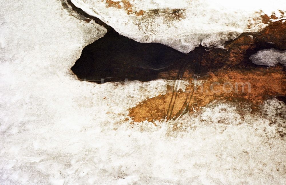 Aerial image Neulewin - Wintry snowy Agricultural fields embossed of soil erosion and ice and snow and water structures in Neulewin in the state Brandenburg, Germany