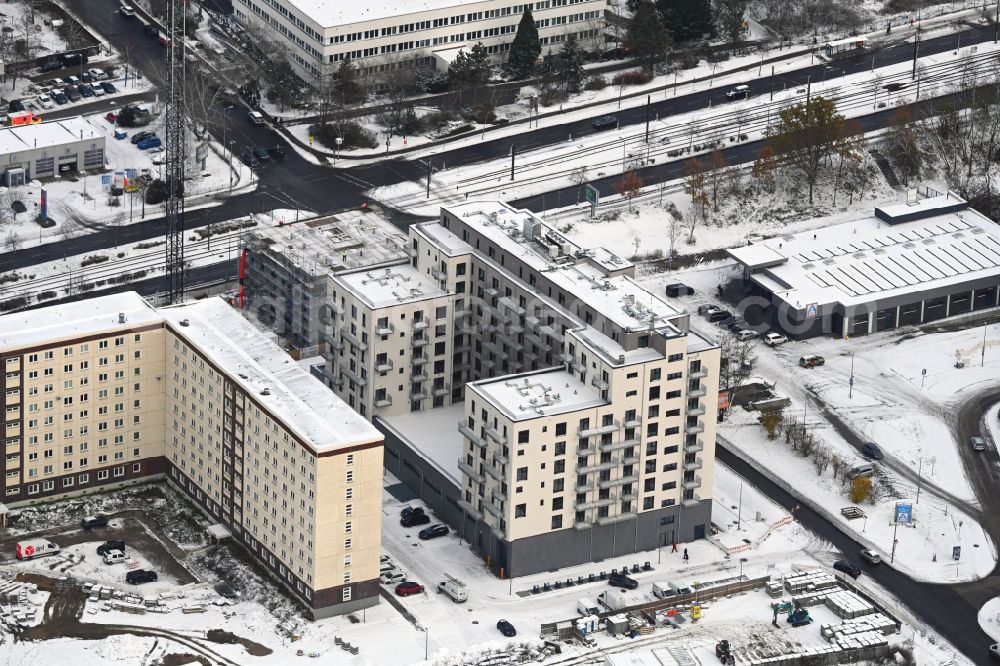 Berlin from the bird's eye view: Wintry snowy construction site for the new residential and commercial Corner house - building on Marzahner Chaussee Ecke Allee of Kosmonauten in the district Marzahn in Berlin, Germany