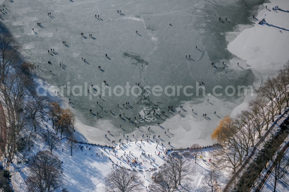 Aerial image Münster - Wintry snowy strollers and passers-by walk on the ice sheet of the frozen bank areas of the lake - surface of Aasee in the district Pluggendorf in Muenster in the state North Rhine-Westphalia, Germany