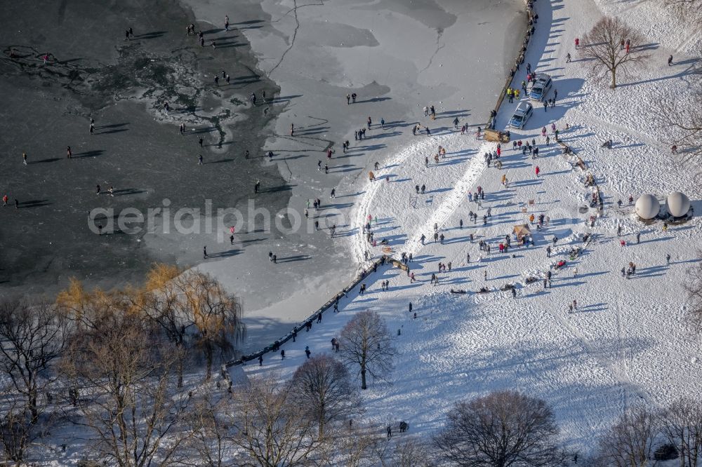 Münster from above - Wintry snowy strollers and passers-by walk on the ice sheet of the frozen bank areas of the lake - surface of Aasee in the district Pluggendorf in Muenster in the state North Rhine-Westphalia, Germany