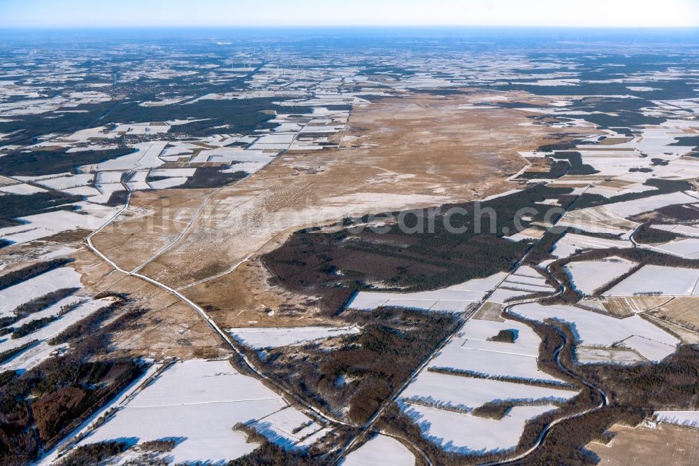 Stavern from above - Wintry snowy agricultural fields with adjacent forest and forest areas of Tinner Dose-Sprakeler Heide in Stavern in the state Lower Saxony, Germany