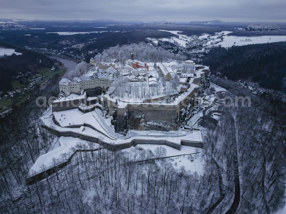 Aerial photograph Königstein - Wintry snowy the Fortress Koenigstein at the river Elbe in the county district of Saxon Switzerland East Erzgebirge in the state of Saxony. The fortress is one of the largest mountain fortresses in Europe and is located amidst the Elbe sand stone mountains on the flat top mountain of the same name