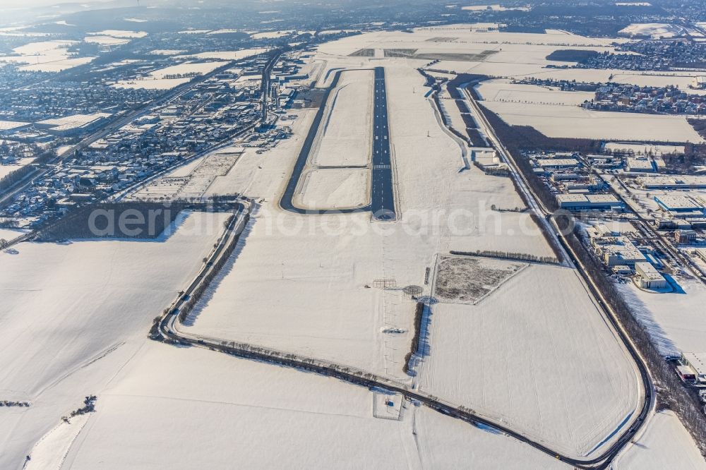 Dortmund from the bird's eye view: Wintry snowy runway with hangar taxiways and terminals on the grounds of the airport in Dortmund in the state North Rhine-Westphalia, Germany