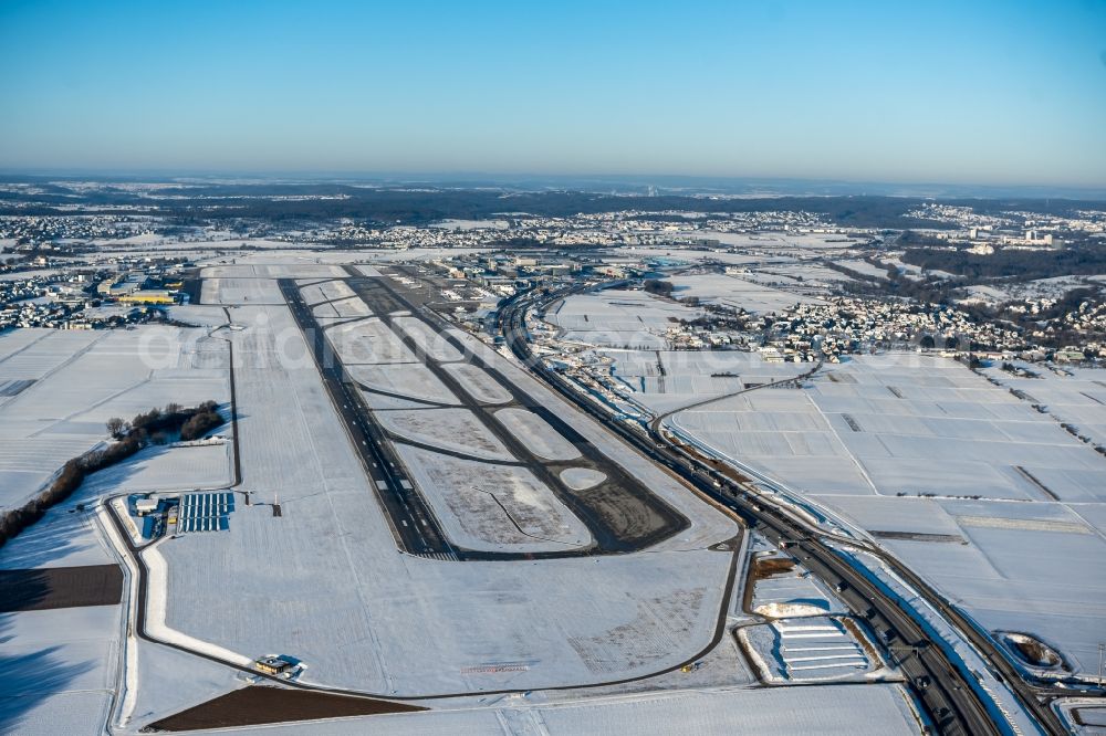 Stuttgart from above - Wintry snowy runway with hangar taxiways and terminals on the grounds of the airport in Stuttgart in the state Baden-Wuerttemberg, Germany