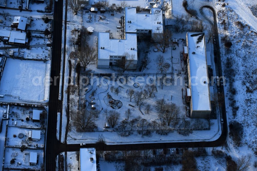 Berlin from above - Wintry snowy park with playground with sandy areas on the Kindergaerten NordOst Zu den Seen on Elsenstrasse in Berlin