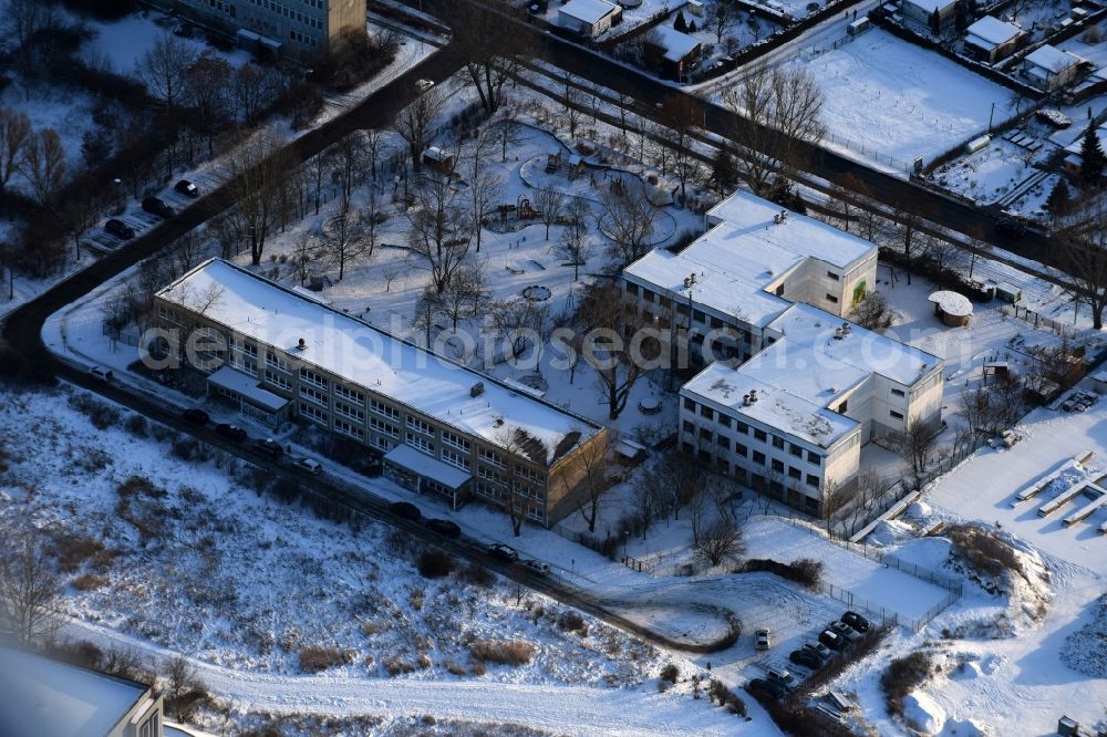 Berlin from the bird's eye view: Wintry snowy park with playground with sandy areas on the Kindergaerten NordOst Zu den Seen on Elsenstrasse in Berlin