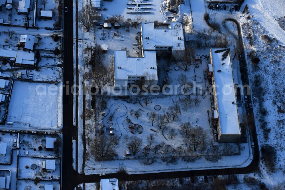 Aerial photograph Berlin - Wintry snowy park with playground with sandy areas on the Kindergaerten NordOst Zu den Seen on Elsenstrasse in Berlin