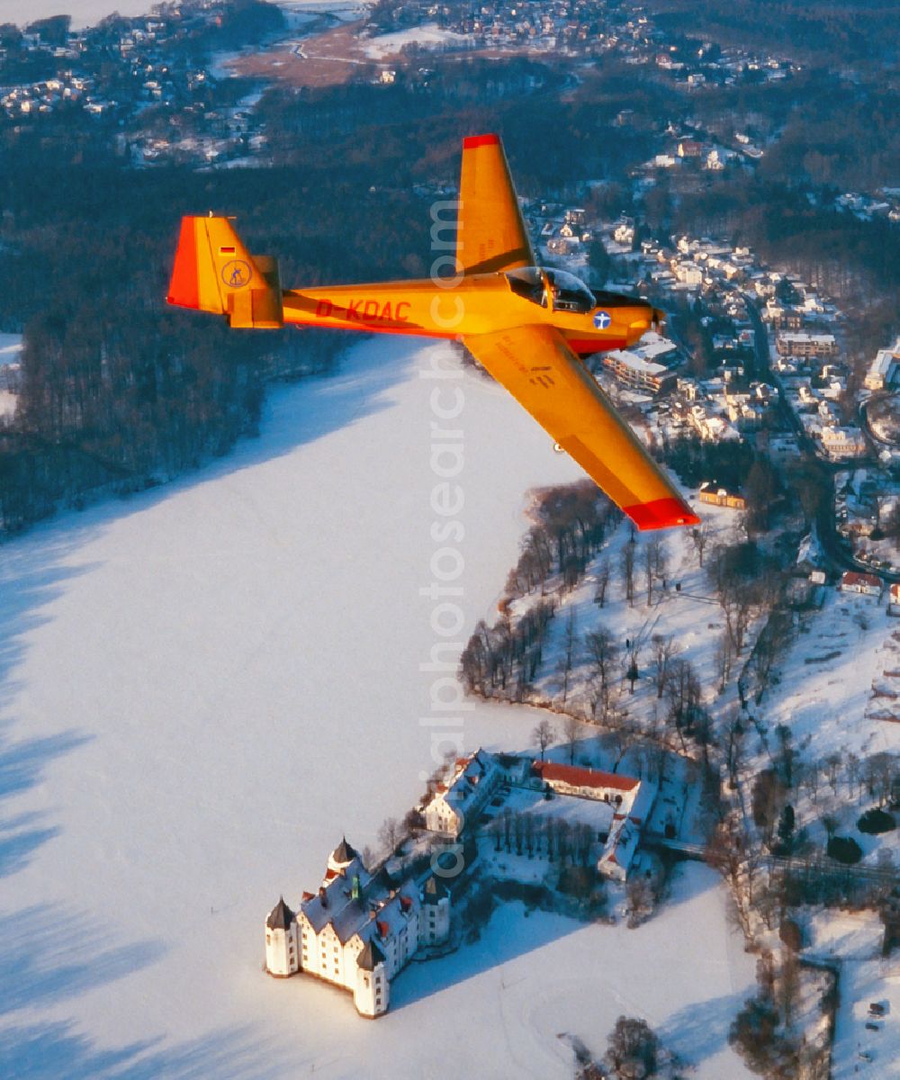 Aerial image Glücksburg - Winter aerial photograph of the motor glider Scheibe SF 25 Falke with the registration D-KDAC in flight over the airspace in Glucksburg in the state Schleswig-Holstein, Germany. Airplane over the snowy landscape at the Gluecksburg Castle pond