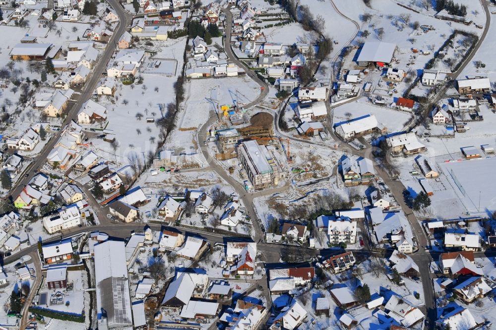 Aerial photograph Minseln - Wintry snowy city view of the streets and houses of the residential areas of Minseln with construction area Weihermatten in the state Baden-Wurttemberg, Germany