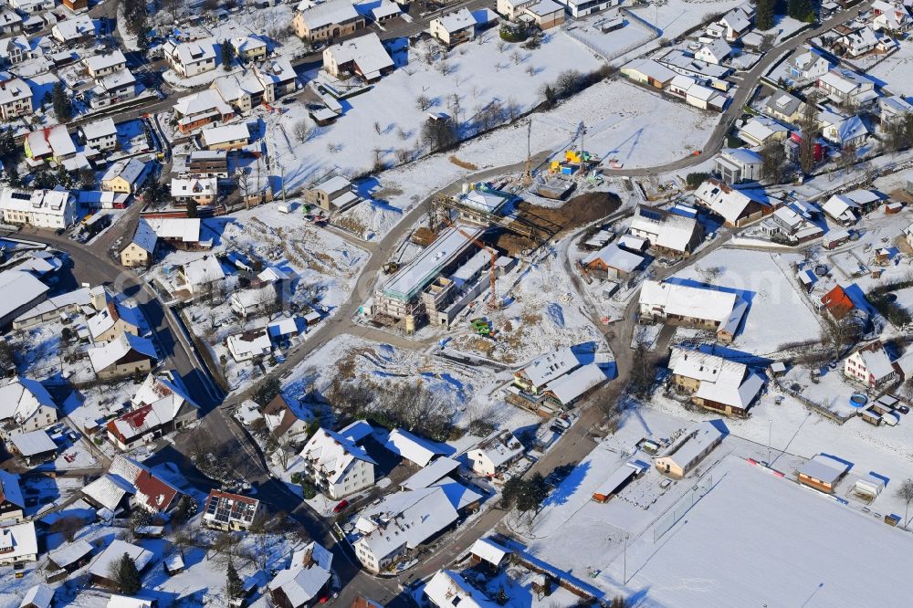 Minseln from above - Wintry snowy city view of the streets and houses of the residential areas of Minseln with construction area Weihermatten in the state Baden-Wurttemberg, Germany