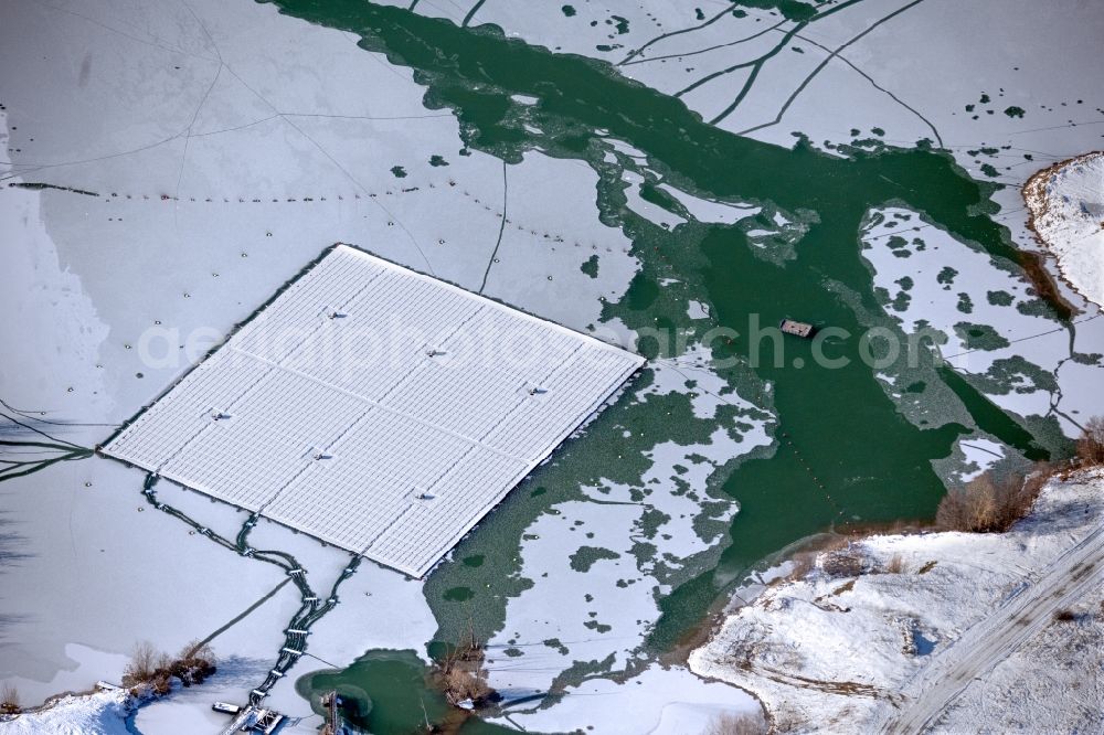 Dettelbach from above - Wintry snowy floating solar power plant and panels of photovoltaic systems on the surface of the water on Dettelbacher Baggersee in Dettelbach in the state Bavaria, Germany