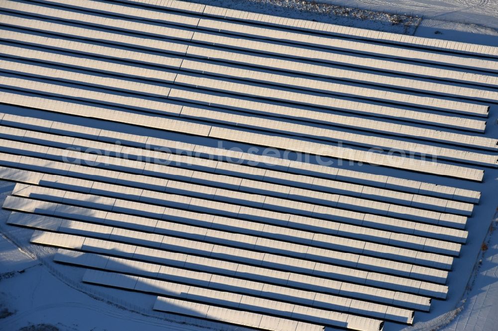 Aerial image Werneuchen - Wintry snowy Panel rows of photovoltaic and solar farm or solar power plant in Werneuchen in the state Brandenburg