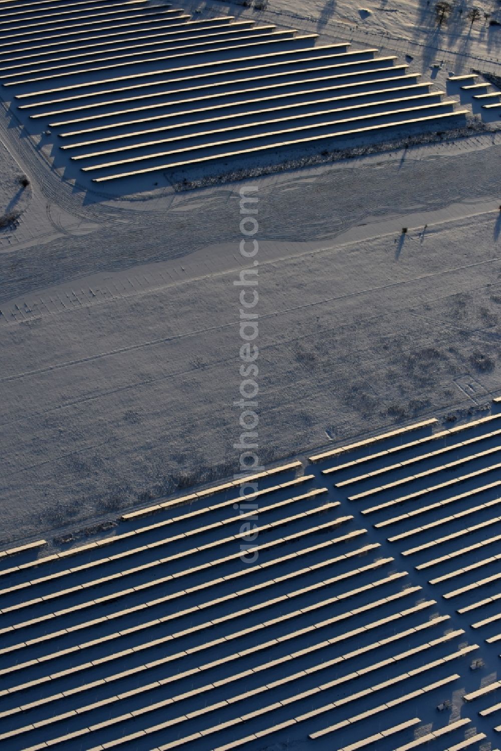 Werneuchen from the bird's eye view: Wintry snowy Panel rows of photovoltaic and solar farm or solar power plant in Werneuchen in the state Brandenburg